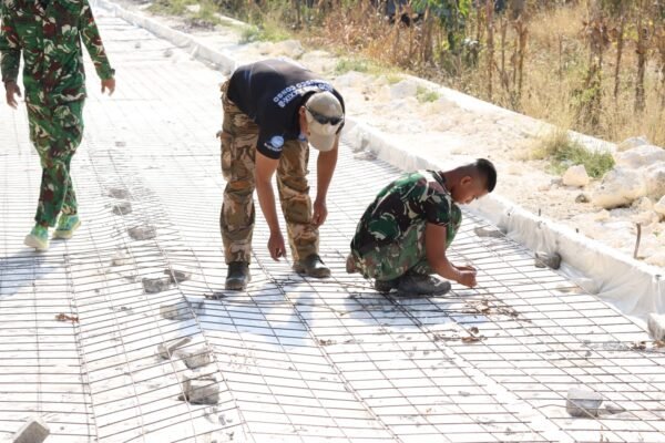 Ketelitian prajurit Satgas TMMD ke 129 dalam bahu-membahu memasang batu penahan di bawah rangkaian besi wiremesh sebelum tahap pengecoran jalan dimulai